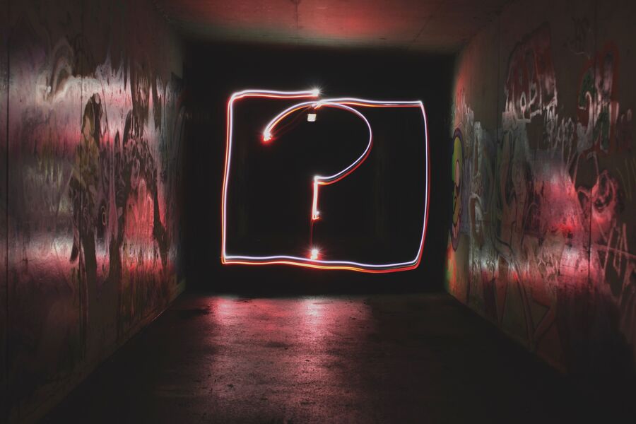 Bilde av et spørsmålstegn i neon i en mørk gang